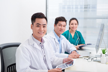 Fototapeta premium Happy doctor man with medical staff at the hospital sitting at office