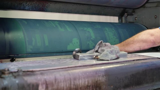 Worker installs new printing plates at the ink rollers of press machine