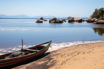 Naklejka na ściany i meble Corner of Catimbaú Beach, with fishing boat and rocks in the background, Paqueta, Rio de Janeiro, Brazil