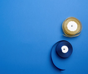spools with blue and golden satin ribbon on a blue background