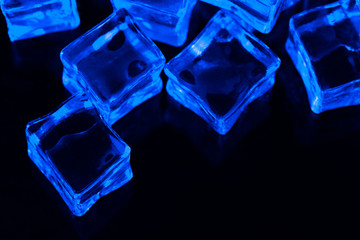 Ice cubes on black background with blue backlight. Illuminated ice cubes.  Macro horizontal...
