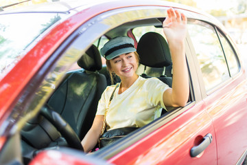 Young woman drive her car greeting with hands