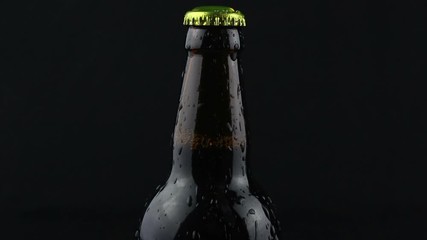 Drops of condensate flow down a beer bottle on a dark background. A misted bottle of beer. Water flows down a bottle of dark beer. - Powered by Adobe