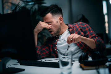 Exhausted businessman in office. Young programmer overworked. 