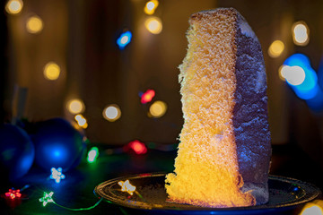 A slice of italian traditional Pandoro pie with Christmas lights.