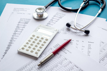 Health insurance concept. Stethoscope near financial documents and calculator on blue background