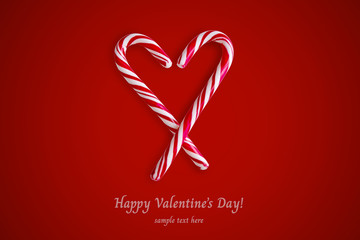 Two red and white candy canes in the shape of heart on a red background.