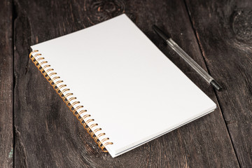 business concept, a notebook for notes with a white sheet and a black pen on a rustic wooden dark brown table