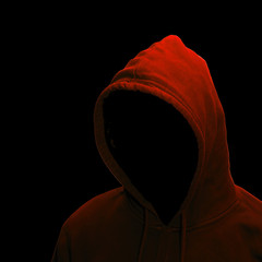Gefährlicher Hacker mit Kapuzenpullover vor schwarzem Hintergrund.