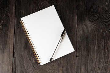 business concept, a notebook for notes with a white sheet and a black pen on a rustic wooden dark brown table