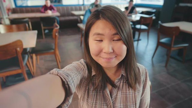 Beautiful asian woman taking selfie on a smartphone. Young asian girl make self photo in cafe or bar