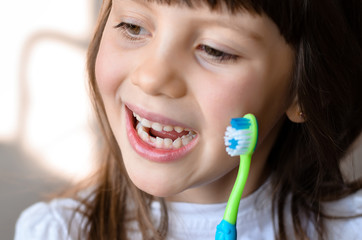 Beautiful smiling preschool girl with her first adult incisor tooth. Cute child showing her baby milk tooth fell out  and her growing permanent tooth in open mouth. Dental hygiene concept