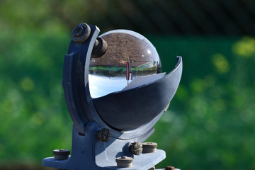 Weather station and the sun in a blue sky reflected in the glass sphere of a beautiful heliograph...