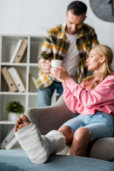selective focus of injured woman near handsome man with cup of tea