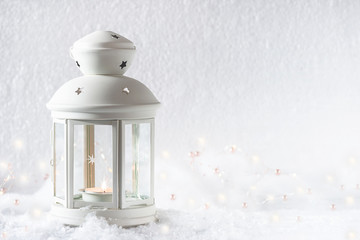 Christmas and New Year greeting card in retro style. White lantern with burning candle on the fresh snow. Copy space, selective focus © stsvirkun