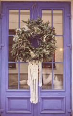 Christmas wreath hanging outside on door in winter made of tree branches, decor, balls and ribbons
