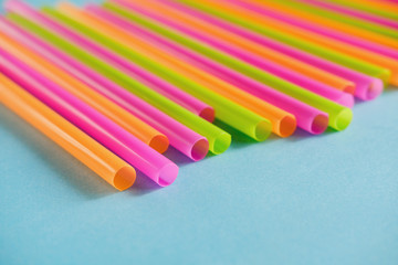 Colorful plastic Drink straws on blue background.  Equipment for single use. Plastic pollution, waste, eco, ecology, recycle. Plastic processing problem. Close up. Copy space