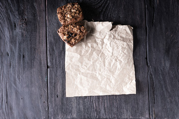 Crumpled kraft paper, oat muffins with chocolate on a wooden table in a rustic style. Culinary business concept