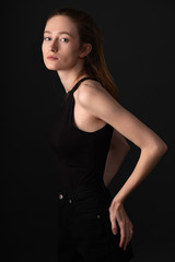 Beautiful brunette model in black clothes posing on dark studio background
