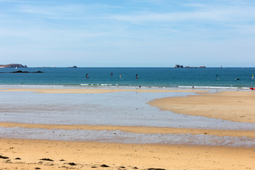 Fototapeta na wymiar Windsurfers surfing along the beach in Saint Malo. Brittany, France