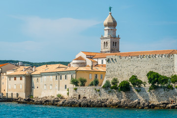View of mediterranean coastal old town Krk with bell tower of the church and fortifications. Krk town is a famous touristic destination on Krk island, Croatia