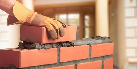 Man worker installing brick masonry wall with a trowel