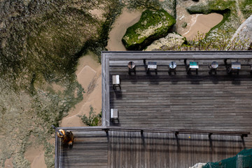 Aerial view of a decked seating area on a beach with a the sea coming in