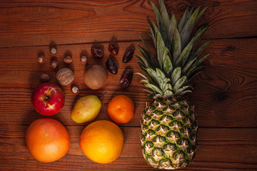 Tropical fruits and nuts vegan diet flatlay. Pineapple, grapefruit, orange, pear, walnuts on wooden background.Healthy weight loss food ingredients.Minimal style.Healthful fats, dietary fiber,vitamins