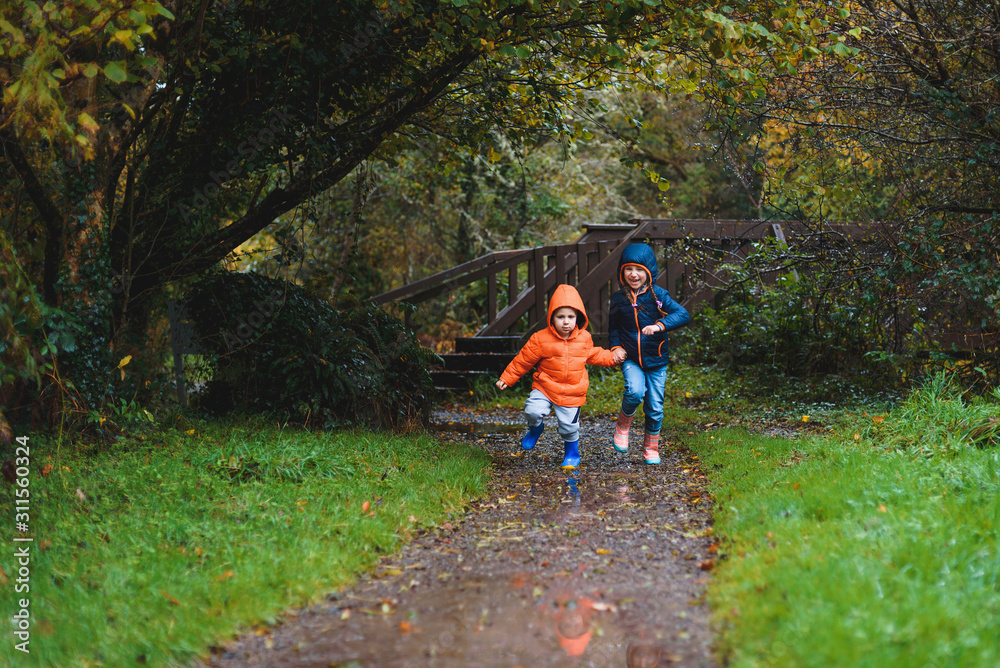 Sticker happy children running in park in rain