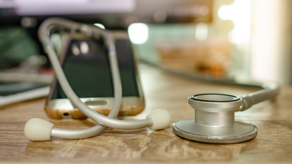 Stethoscope with mobile phone put on the table.  Concept of consulting health problems or doctors online.