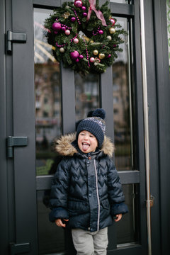 Boy Standing Next To A Hi-tech Gray Front Door With A Christmas Wreath