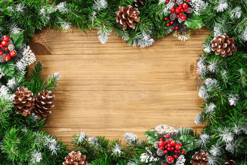 Christmas border composed of snow-covered fir branches and cones on christmas wooden background. Winter holiday background. Top view. Flatlay. Copy space for text