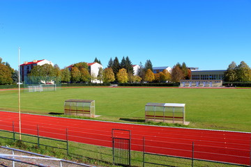 Stadium. Green soccer field, treadmill, sports field on a background of blue sky and green plants.