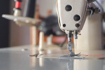 Needle of white industrial sewing machine use sew cloth close-up.