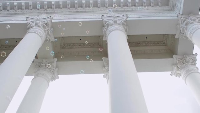 Many soap bubbles fly on the background of the classical portico with columns, constancy and variability, concept