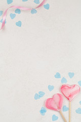 two pink hearts as lollipop candy with blue hearts around on white background.
