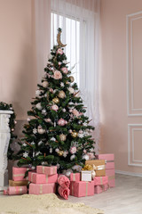 Christmas tree with a lot of gifts in the room near the fireplace.