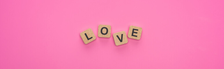 top view of love lettering on wooden cubes on pink background, panoramic shot