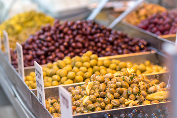 Green and brown and red and black olives in metal bowls on a blurred white background, made of Syrian-Arab style. In the market in Jerusalem.