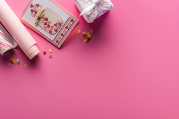 top view of valentines decoration with greeting card and present on pink background