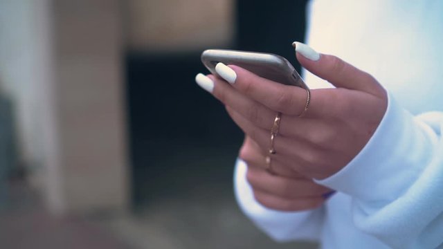 Close up of woman's hand holding a mobile phone. Beautiful long nails, manicure. The girl uses a smartphone for online shopping.