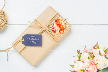 Mockup kraft gift boxes with tag on white wooden background with Happy Valentine's Day text on postcard. Mock up for elegant design. Flat lay top view valentine's day background concept.