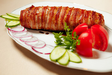 pork neck roll stuffed with cheese and vegetables in bacon