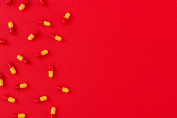 Red-orange pills in capsule on red background, flat lay, top view, copy space