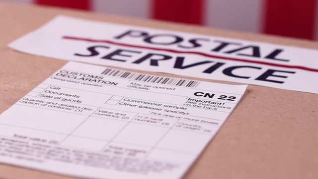Parcel with a label and Customs declaration form CN22 on a American flag background. Close-up