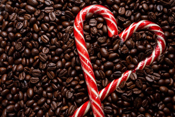 background of roasted coffee beans. A heart made of a Christmas cane. Sweet lollipops