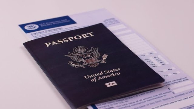 Man puts an American passport with a customs declaration form on a white background. Close-up