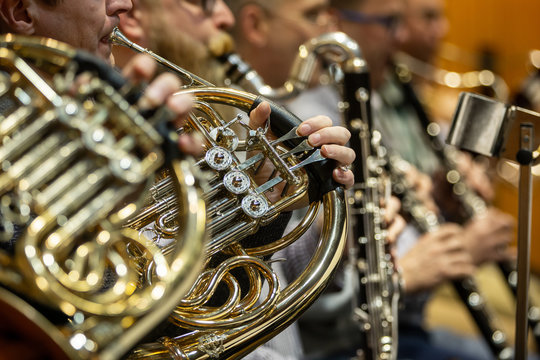Detail of orchestra, philharmoic player playing on french-horn during huge philharmonic concert (shallow DOF)