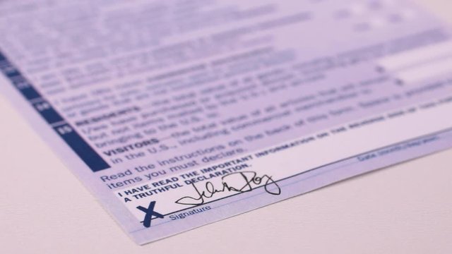 Man fills Customs Declaration Form, puts a signature. Close-up