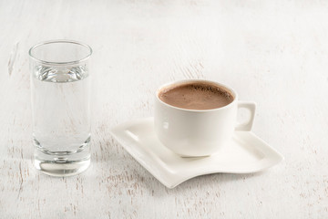 Turkish coffee served with a glass of water on table